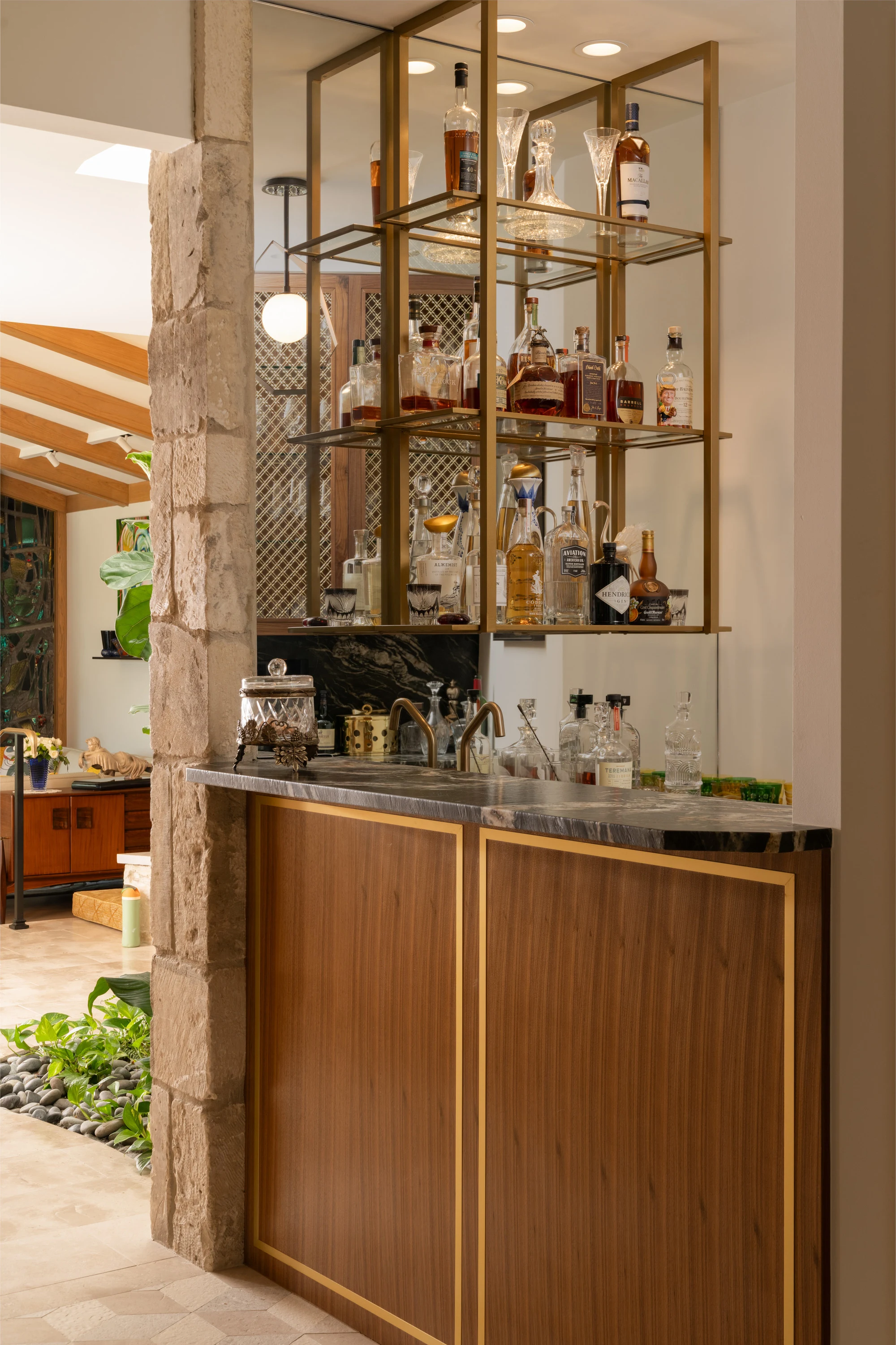 Brass and glass bar shelving against the stone wall