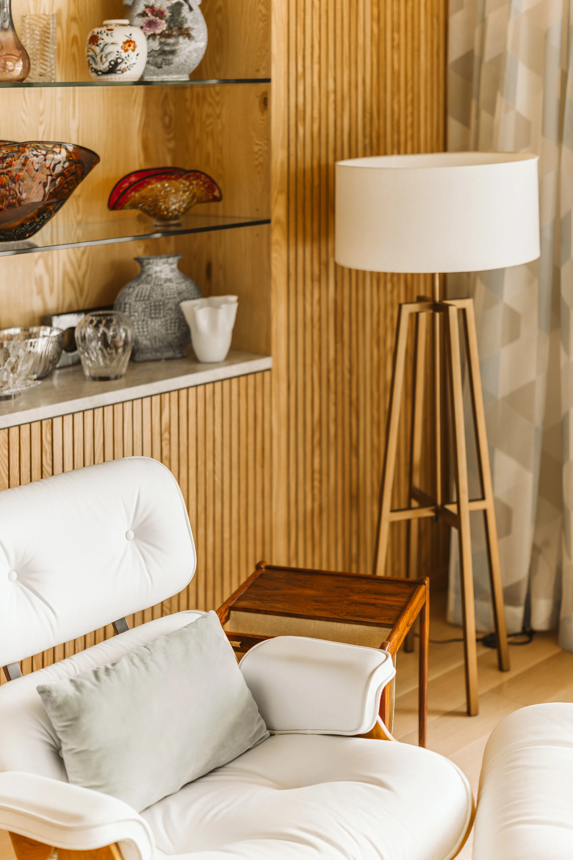 White leather lounge chair beside fluted timber and open shelving